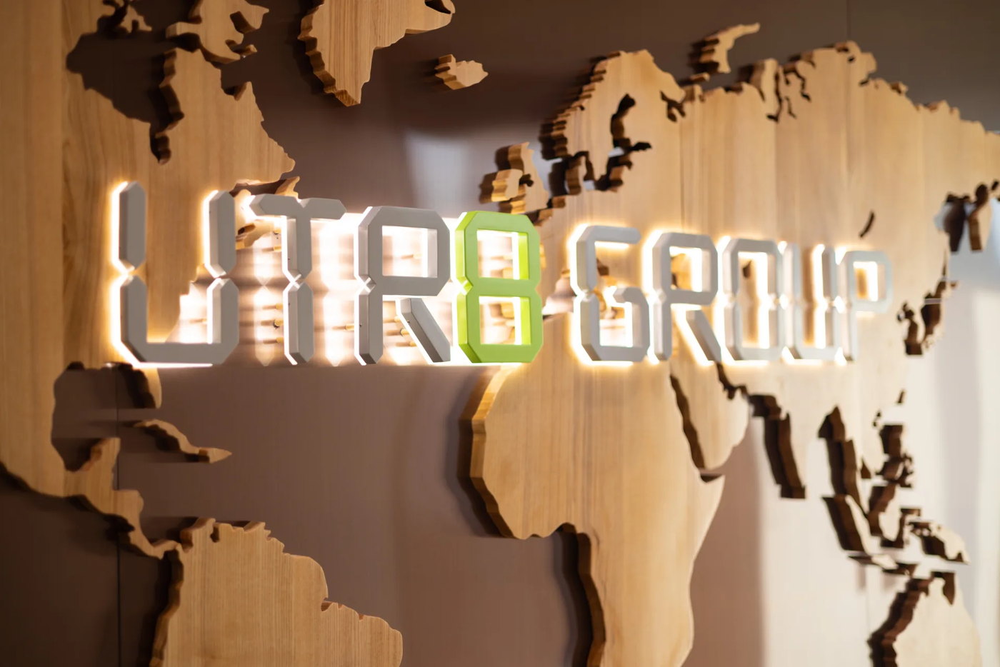 The UTR8 Group sign lit against a wooden relief map of the world